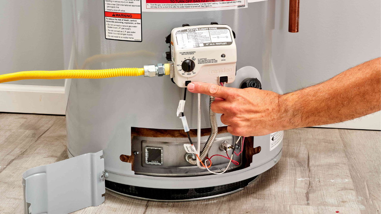 A man adjusting a water heater on the floor.